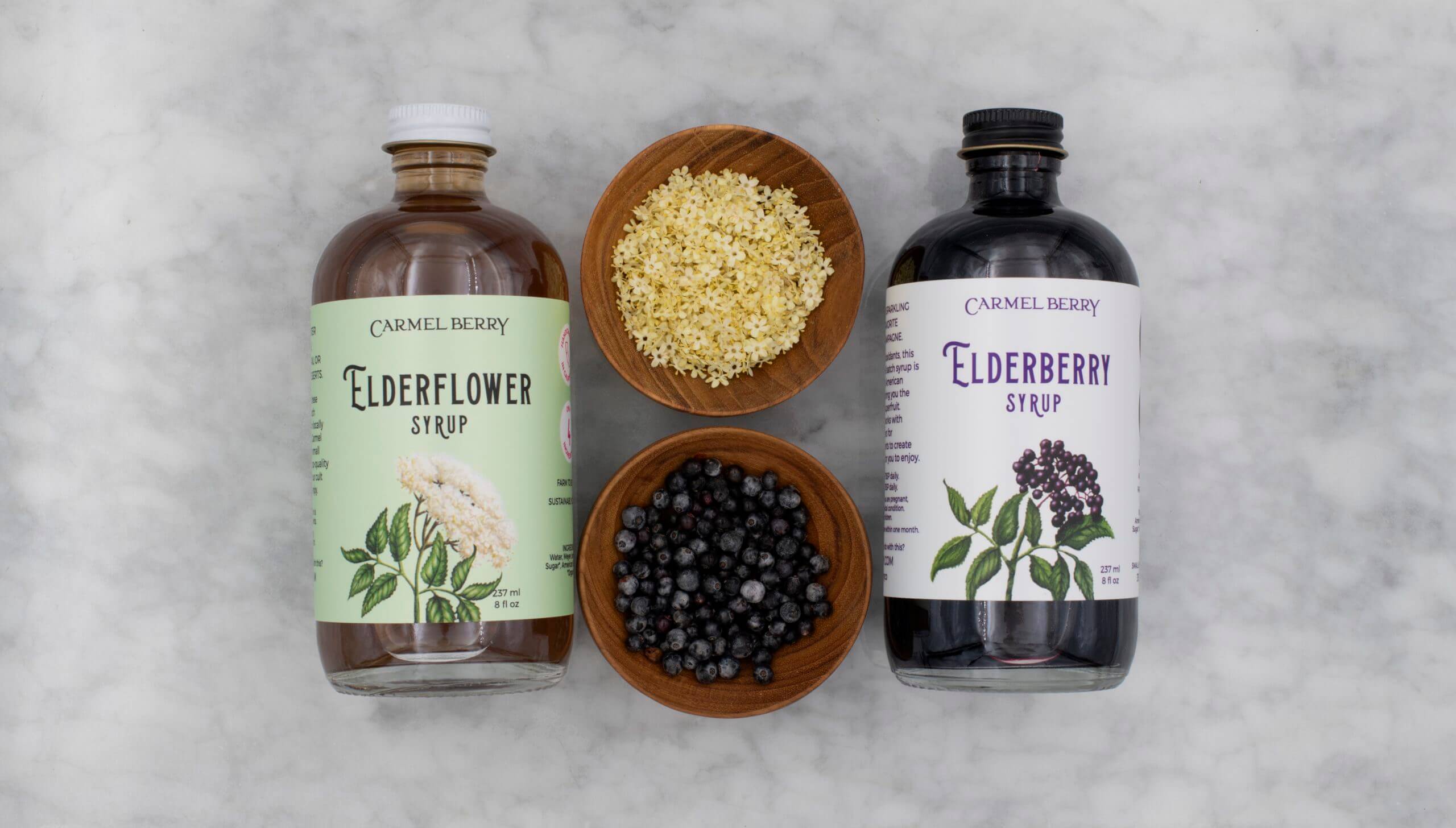 Carmel Berry Elderflower syrup and elderberry syrup with bowls of ingredients