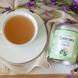 Carmel Berry Elderflower Comfort Herbal Tea tin and tea cup